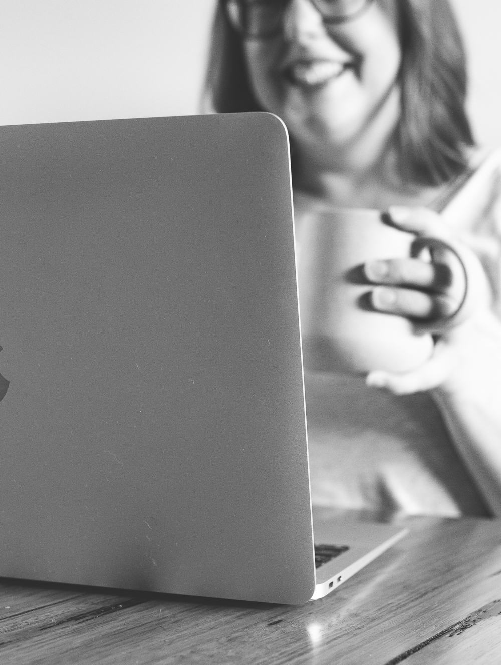 Nina Mills website designer, copywriter and SEO from Butter Digital sitting at a desk smiling at a laptop and holding a coffee.