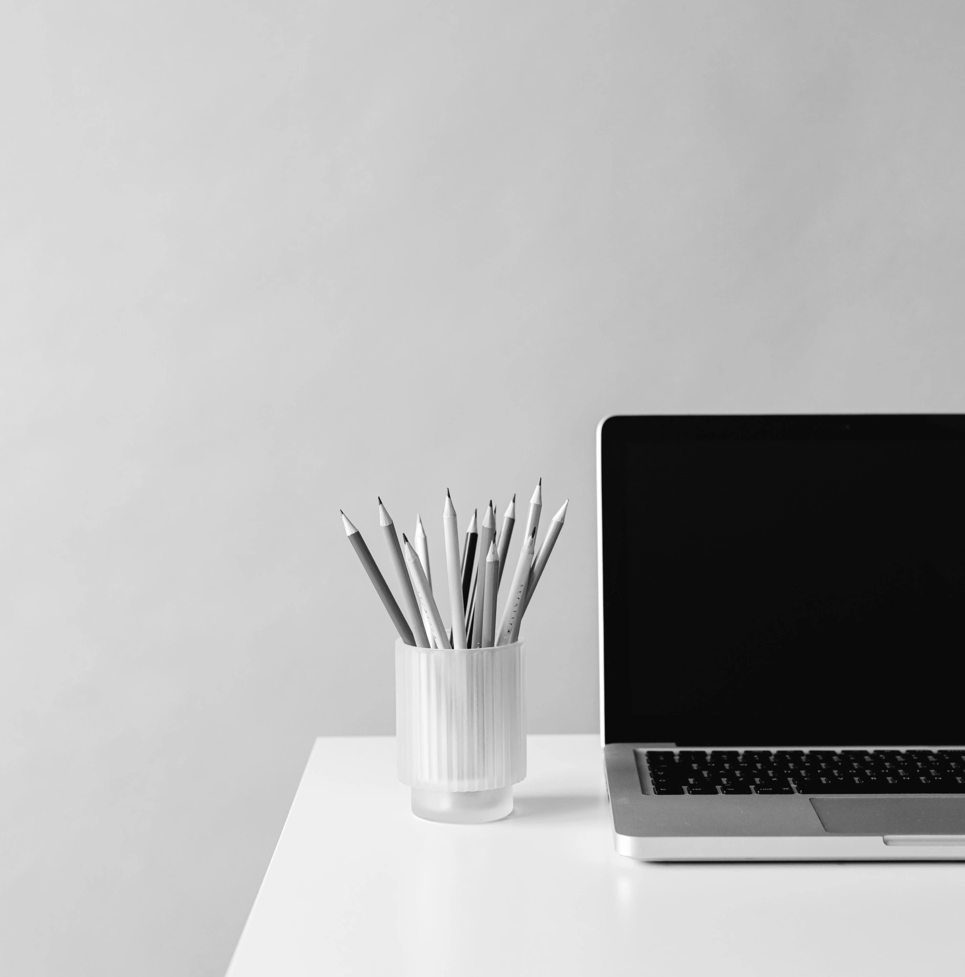 A desk setup for a website copywriter with laptop and jar of pencils.